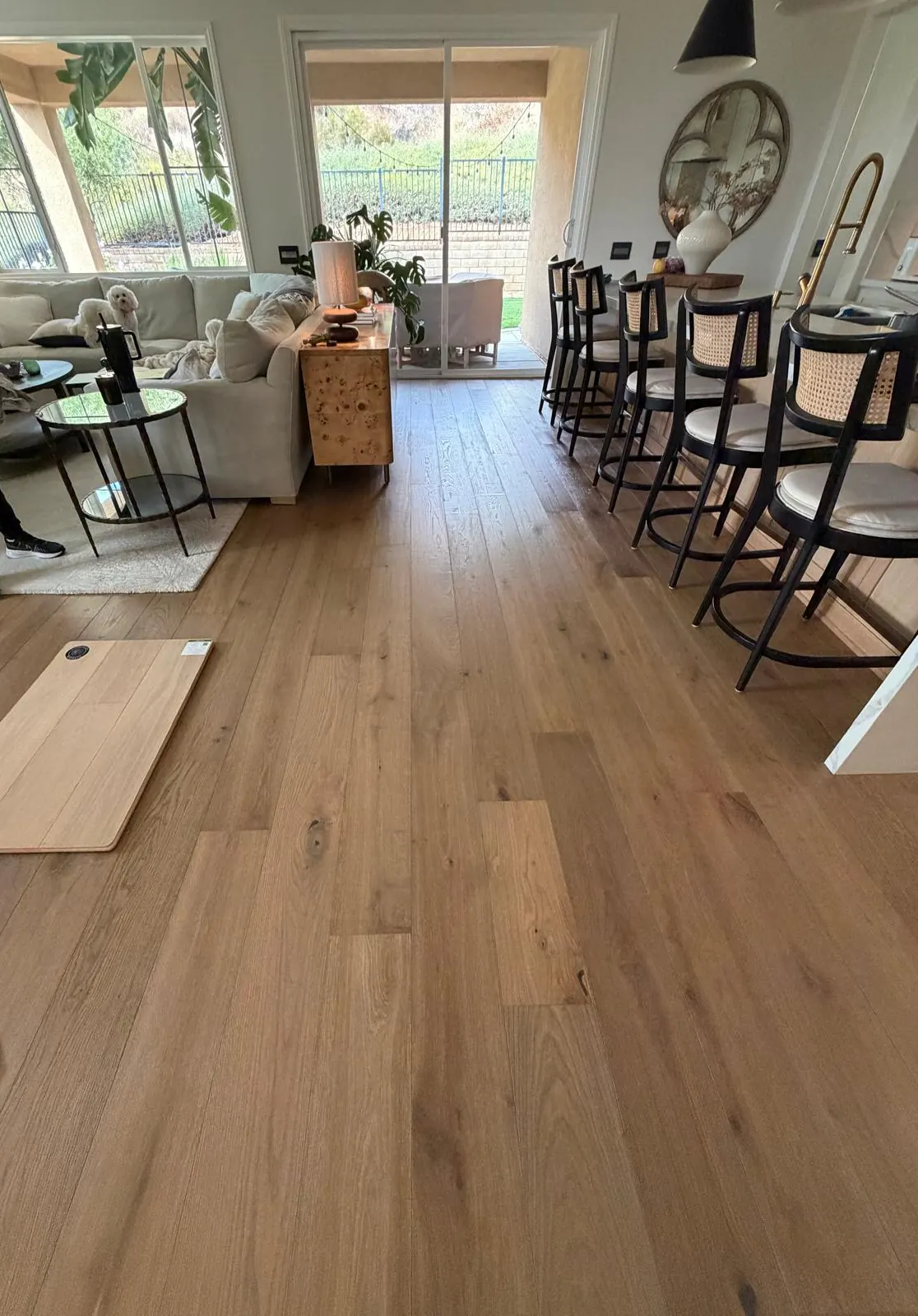Freshly installed wide plank wood-look floor running through a bright living and dining area