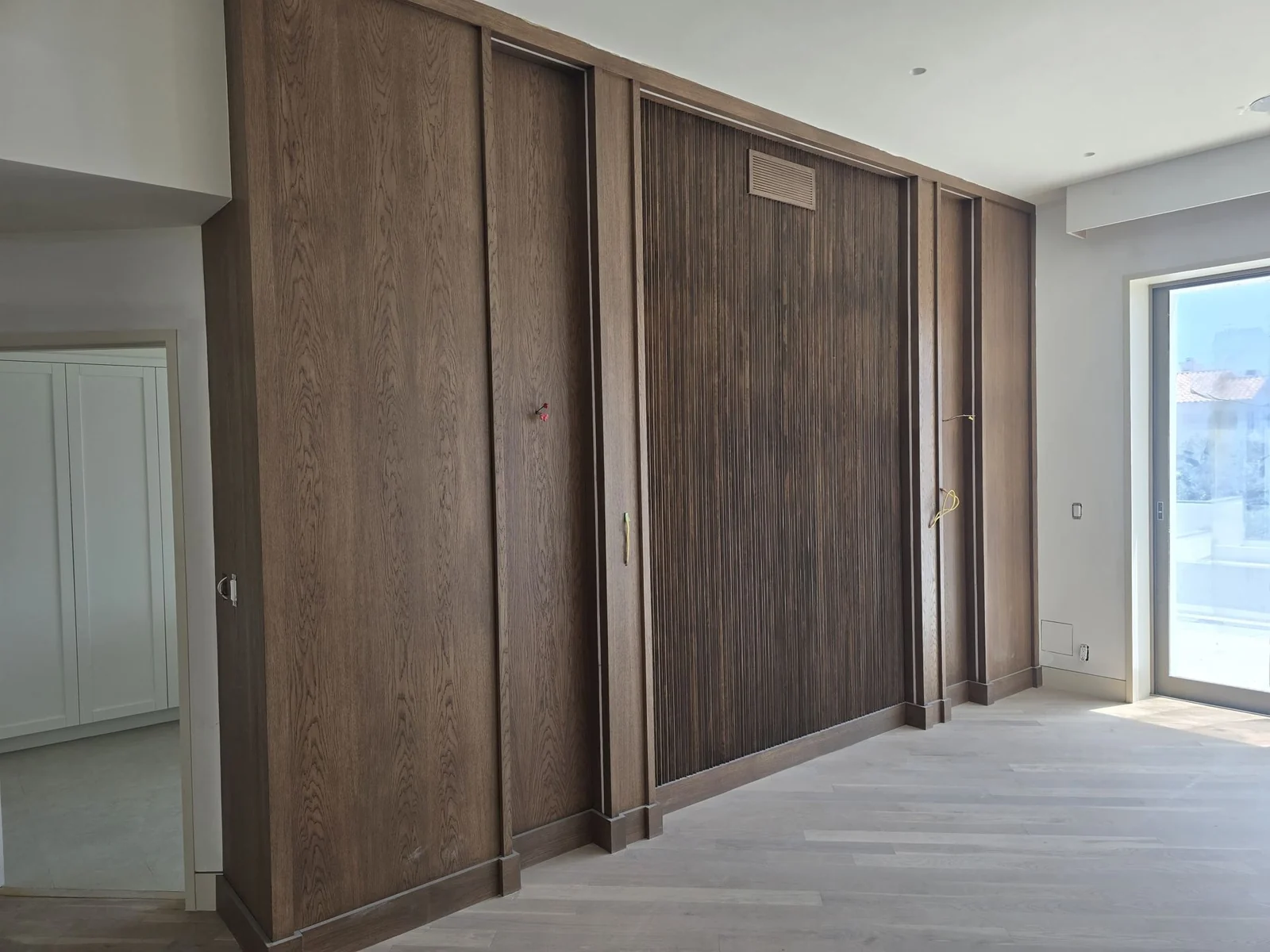 Floor to ceiling wood panel wall above a light plank floor