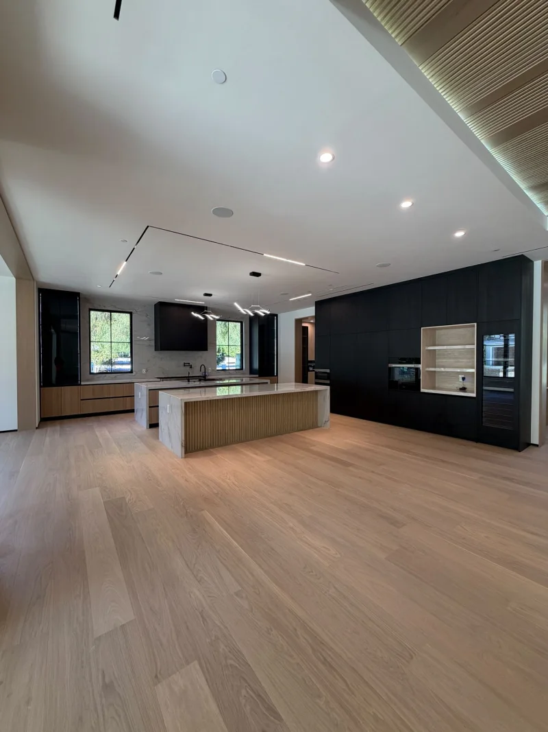 Open great room with wide light oak planks running from the living area to the kitchen island
