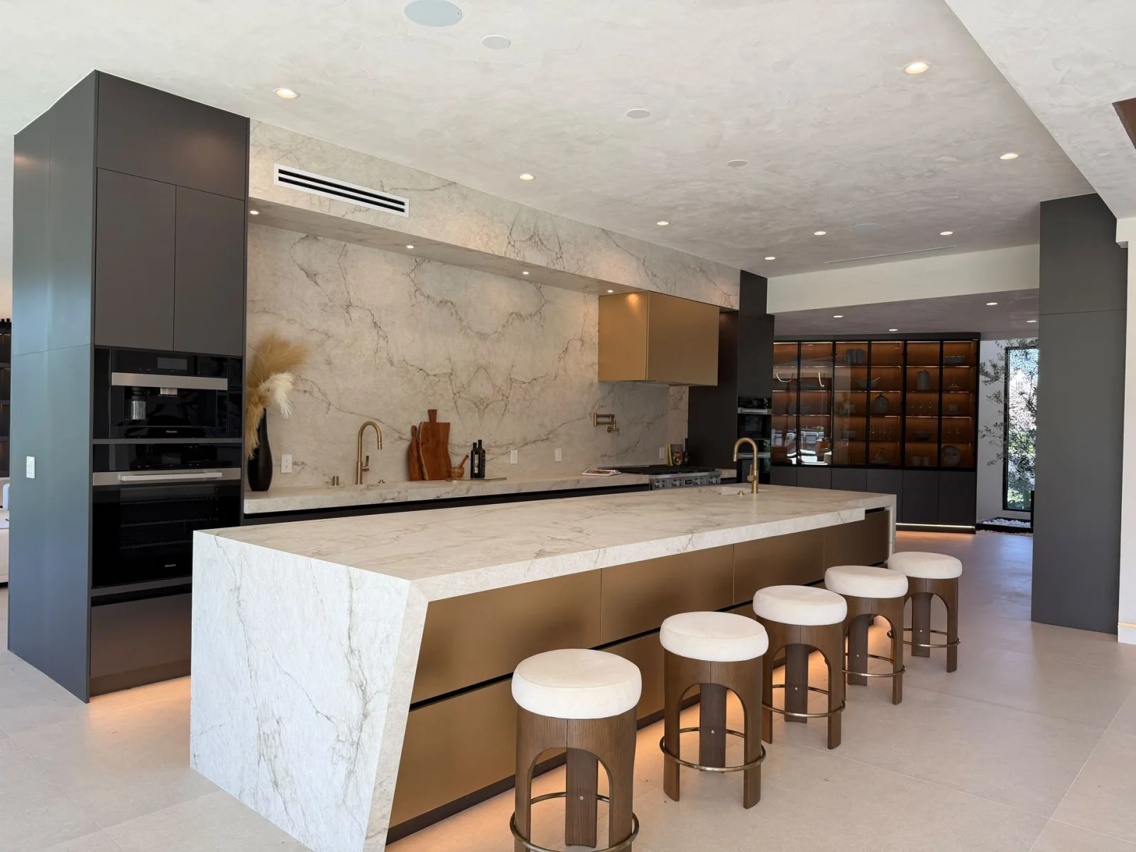 Warm wood-toned flooring around a kitchen island with dark cabinets